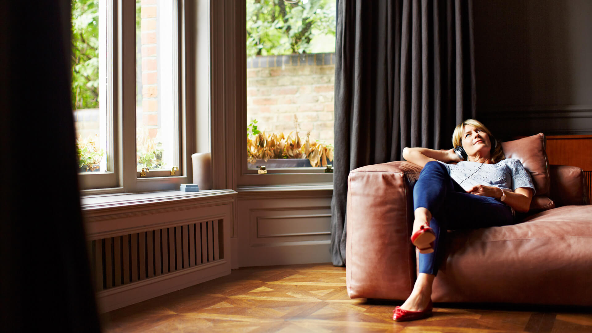 Woman On Sofa With Bay Window Listening To Music 